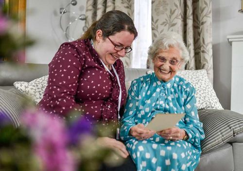 carer and client laughing and smiling over gift